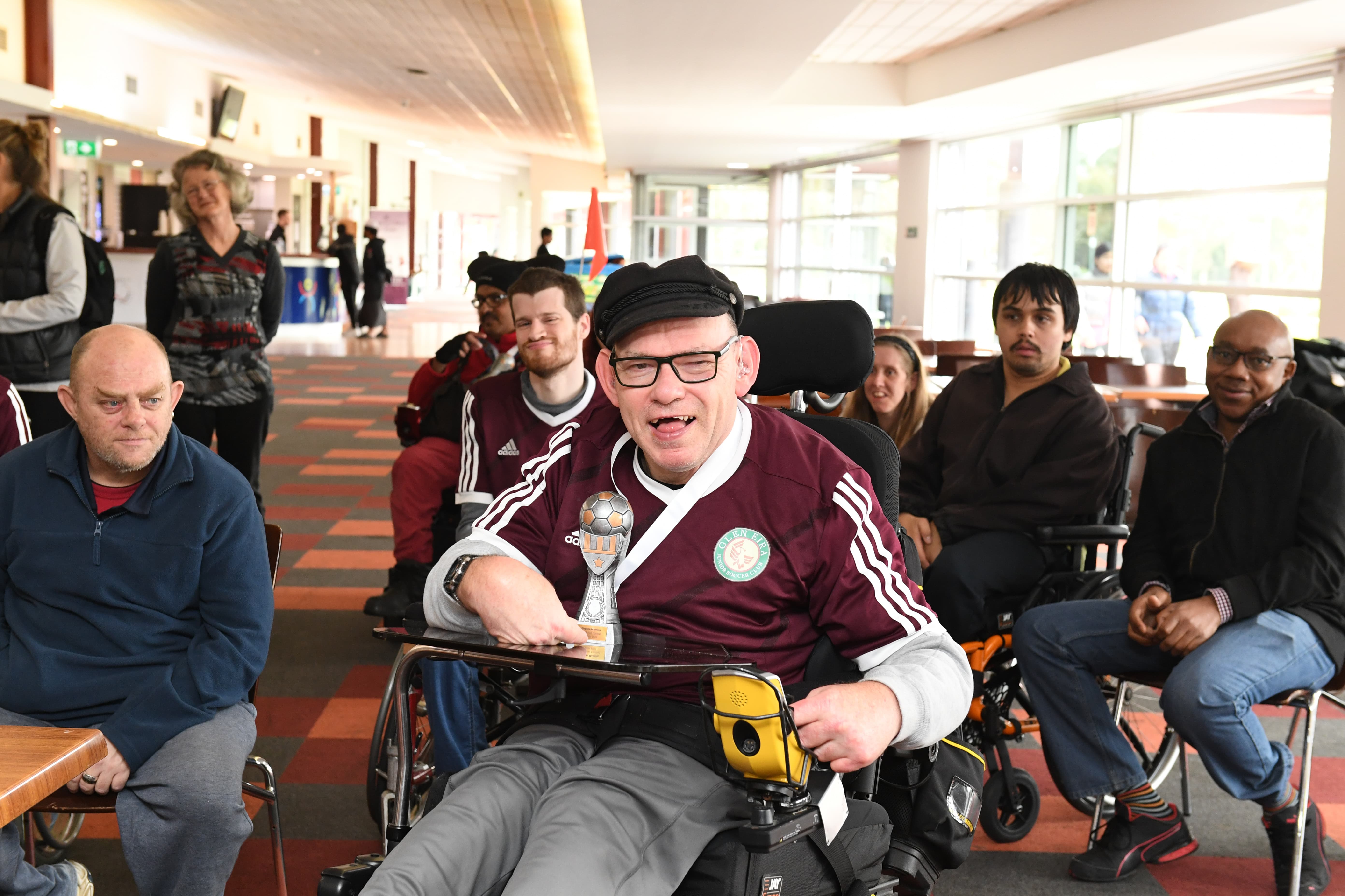 Wheelchair football player posing with a trophy