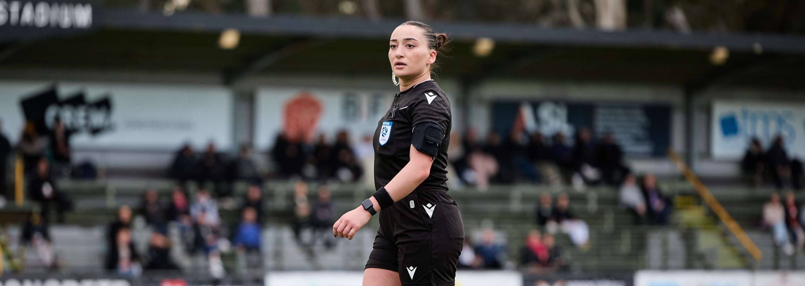 Female Referee wearing black officiating a match in the day