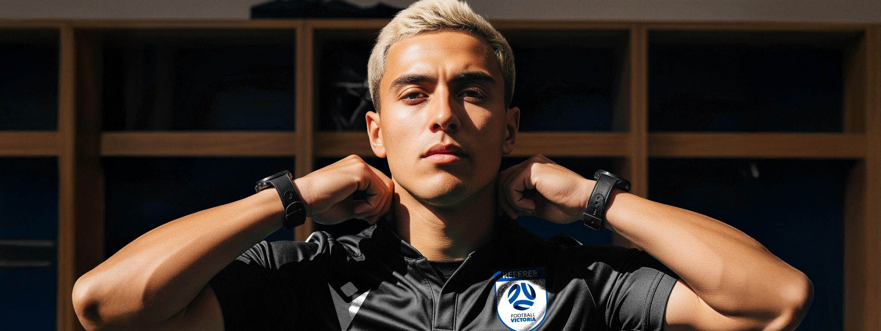 Male wearing black and in a change room, getting ready to officiate a match