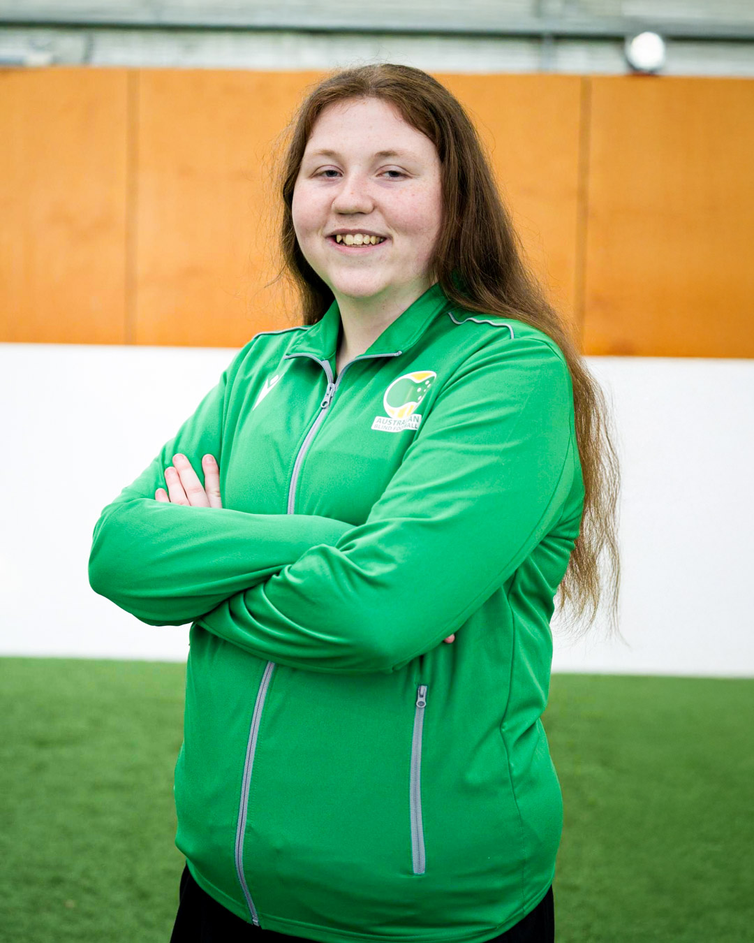   Charlotte posing with arms crossed in green Bilbies jacket   Charlotte standing at the stands of AAMI Stadium with the pitch and stadium in the background