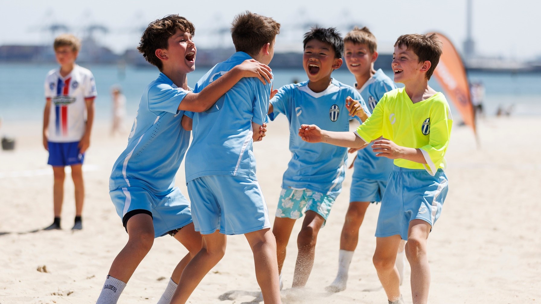 Boys cheering after a goal, playing beach football.