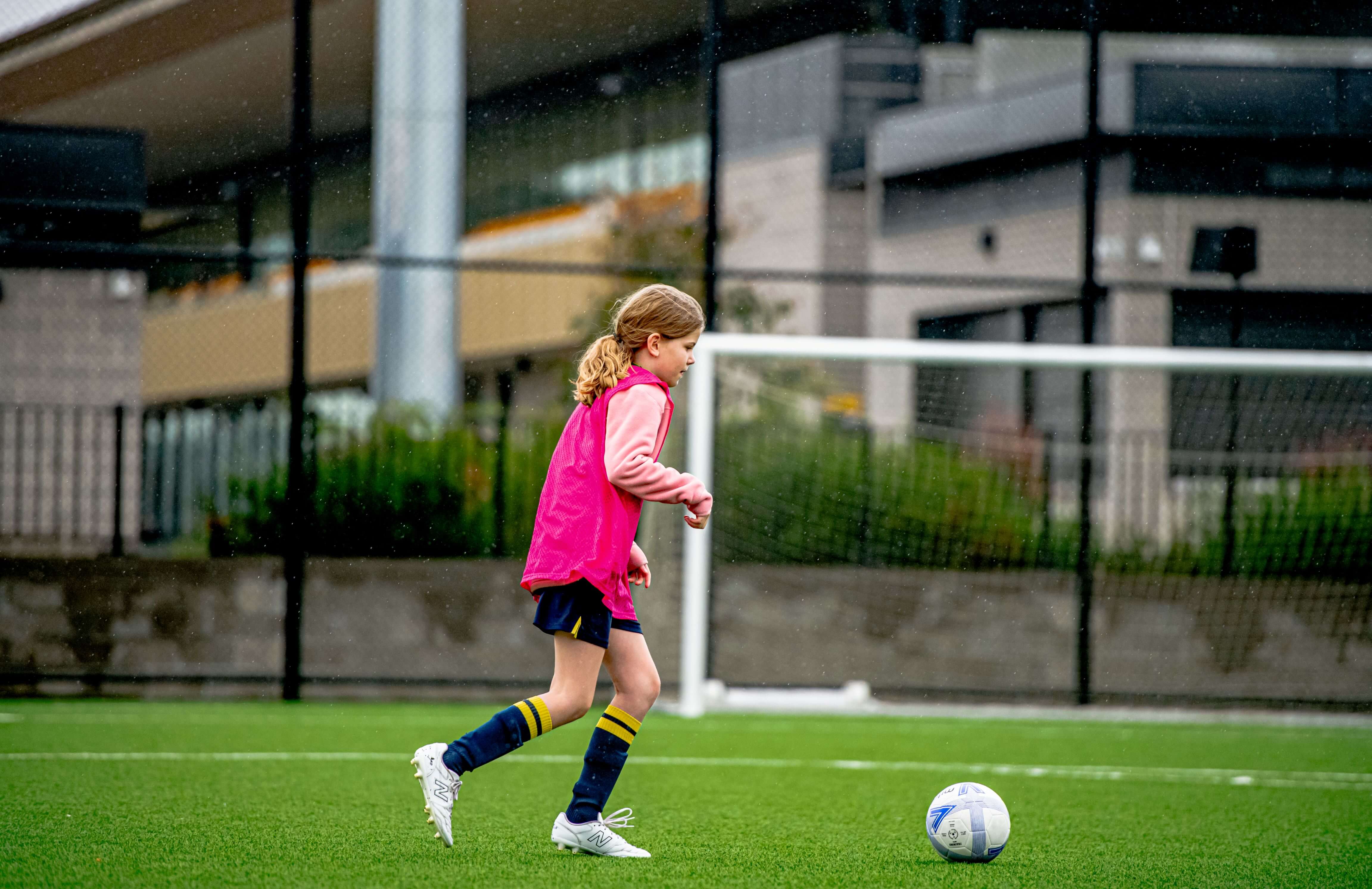 Young female soccer player kicking a ball on a soccer field