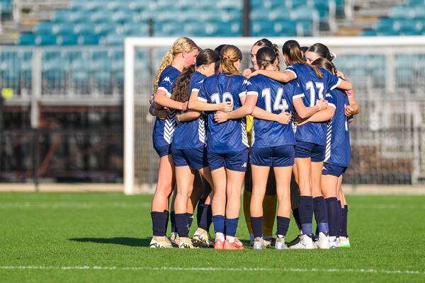 FV Academy Girls in group hug, on The Home of The Matildas pitch